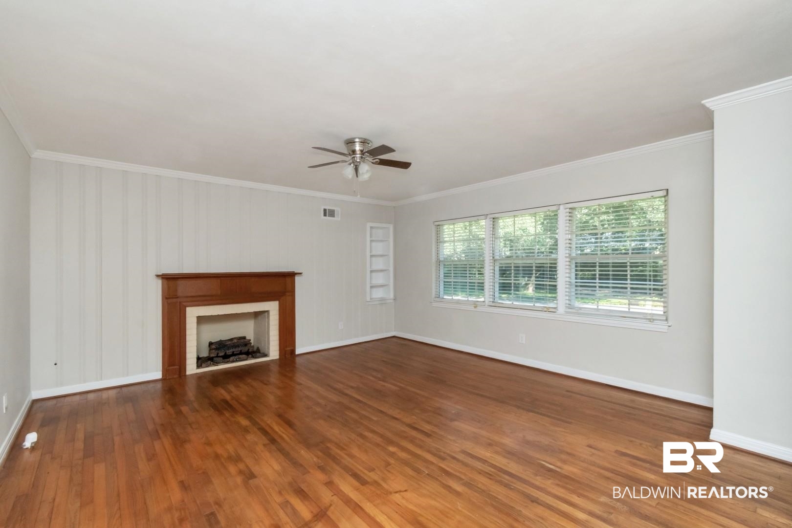 2105 Upham Court Mobile, AL 36607 - Photo 6 of 32 Unfurnished living room featuring ornamental molding, a fireplace, dark wood-style flooring, and a ceiling fan
