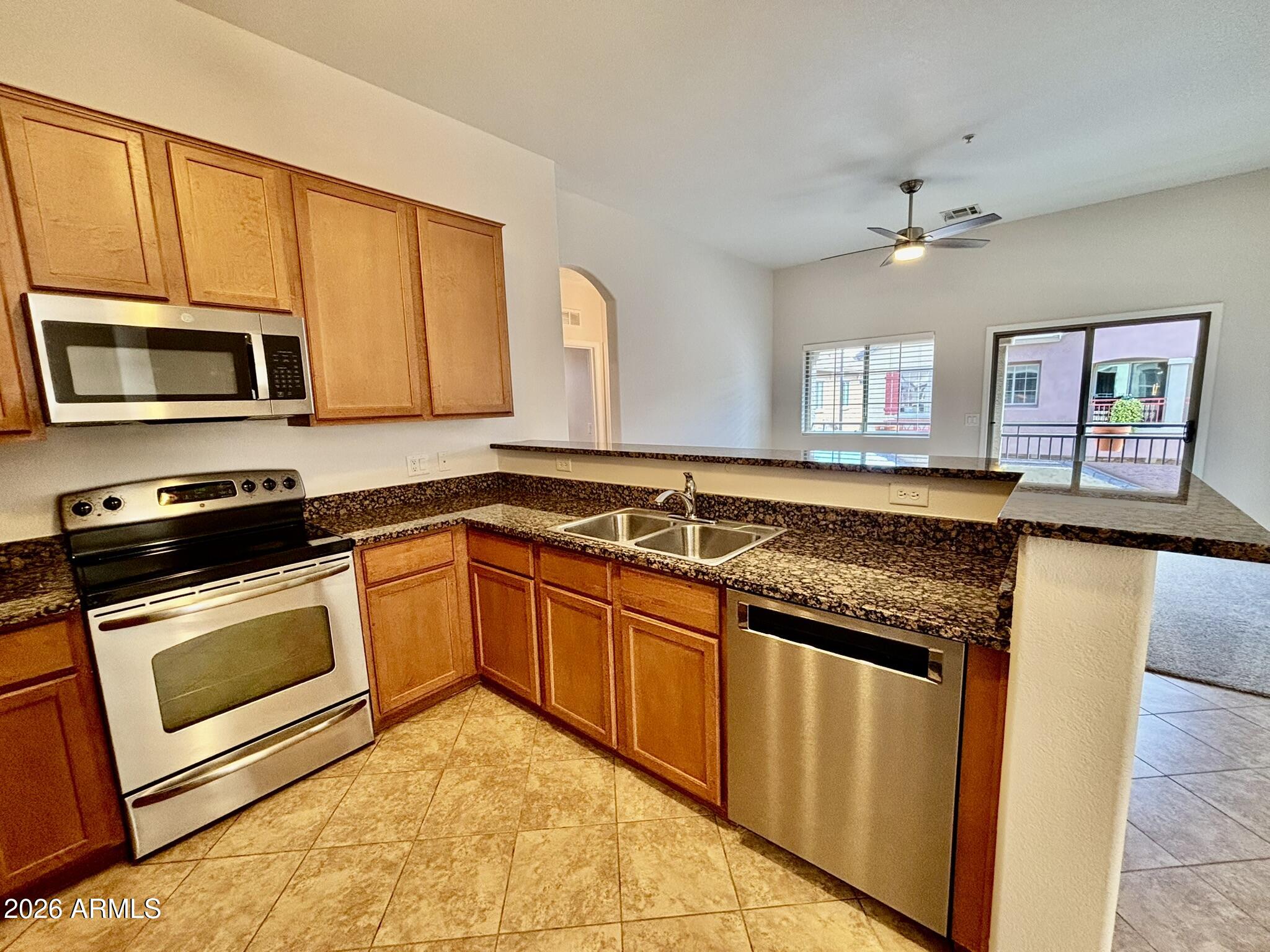 1350 South Greenfield Road, Unit 2041 Mesa, AZ 85206 - Photo 5 of 33 a kitchen with granite countertop a stove sink and microwave
