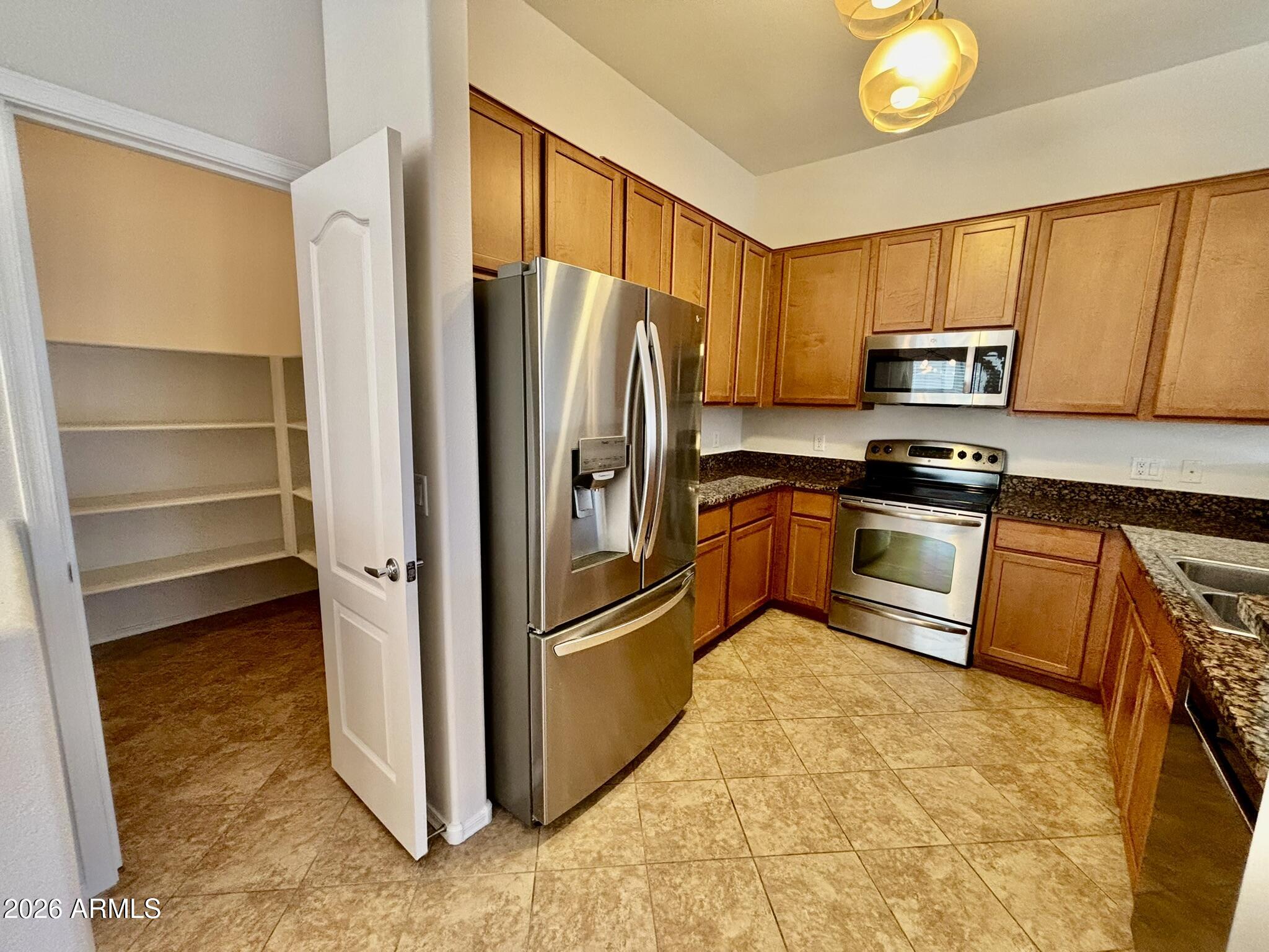 1350 South Greenfield Road, Unit 2041 Mesa, AZ 85206 - Photo 9 of 33 a kitchen with granite countertop a refrigerator and a stove top oven