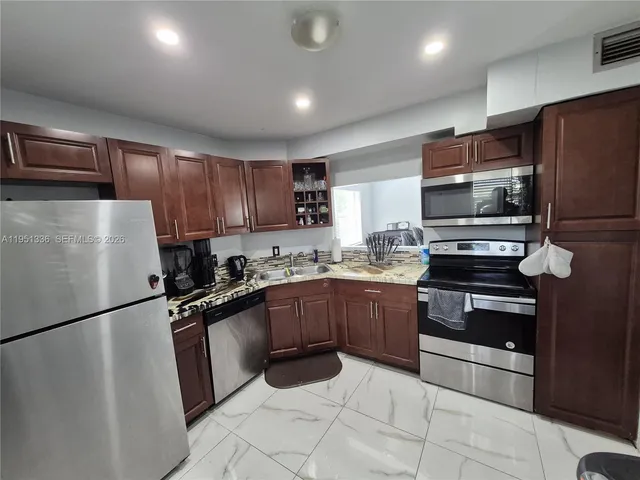 a kitchen with granite countertop a refrigerator stove and microwave