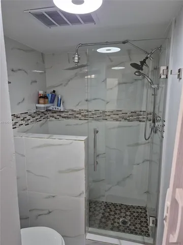 a bathroom with a granite countertop sink a toilet and shower