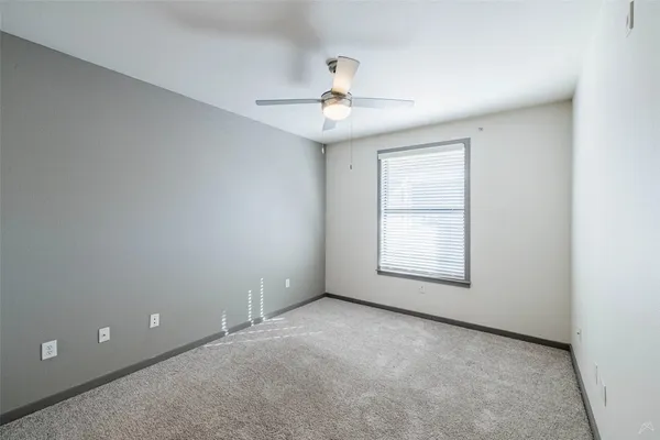 an empty room with a window and ceiling fan