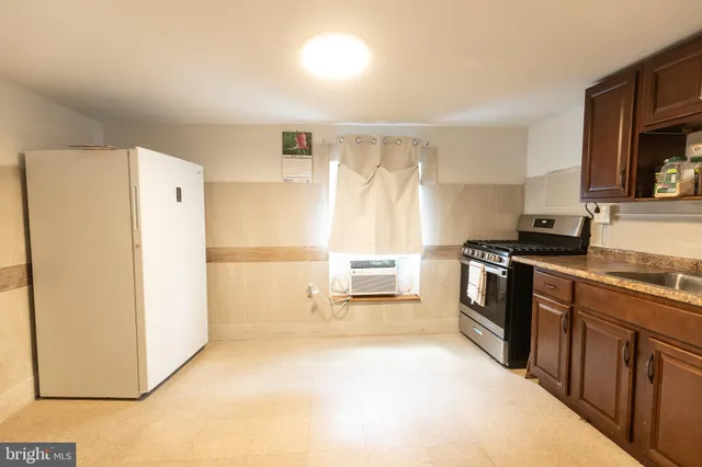 a kitchen with granite countertop a refrigerator a sink a stove and wooden cabinets