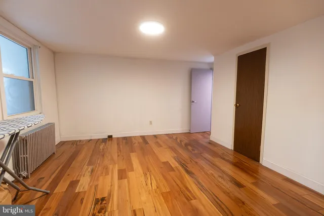 a view of an empty room with window and wooden floor