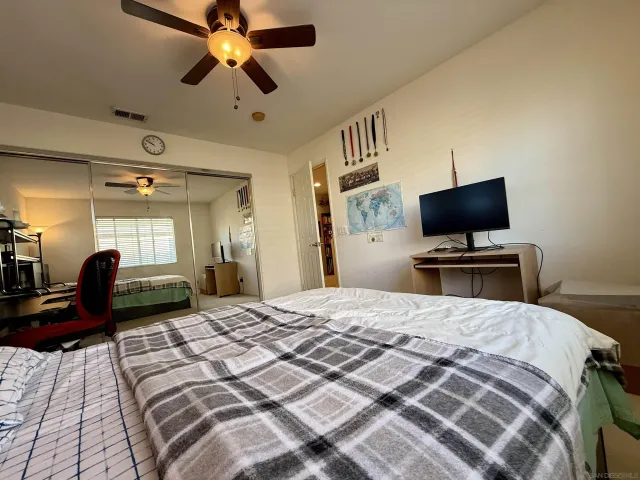 a bedroom with a bed a chair and potted plant on the dresser
