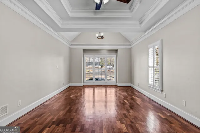a view of empty room with wooden floor and fan