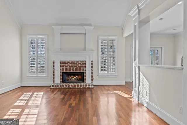 a view of an empty room with wooden floor fireplace and a window