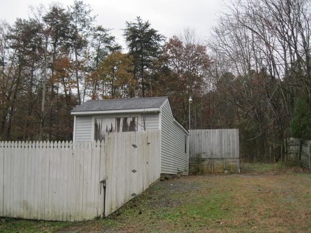 1261 Mountain Pass Road Blue Ridge, VA 24064 - Photo 3 of 23 a view of a small house with wooden fence and large trees