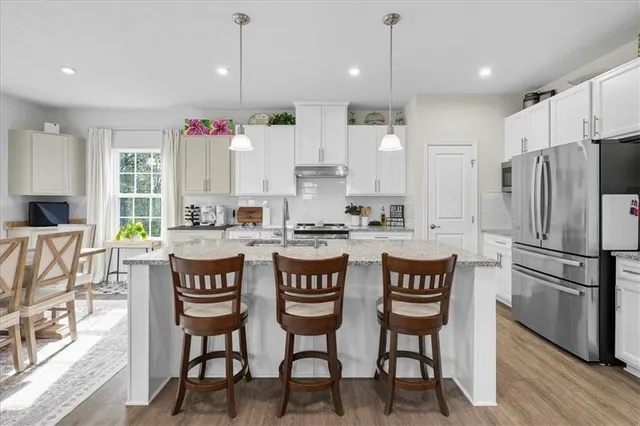 a kitchen with stainless steel appliances granite countertop a stove a refrigerator a kitchen island a dining table and chairs