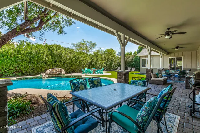 a view of a backyard with table and chairs potted plants and large tree