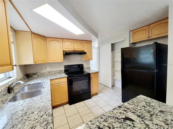 a kitchen with granite countertop a refrigerator and a stove top oven
