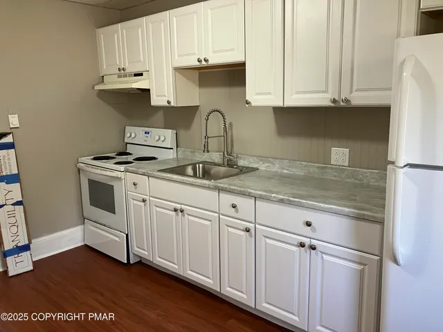 a kitchen with white cabinets and a stove with wooden floors