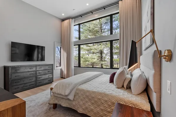 a bedroom with a large bed and a flat tv screen on dresser