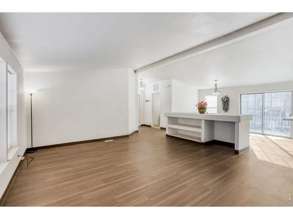 a view of an empty room with window and wooden floor