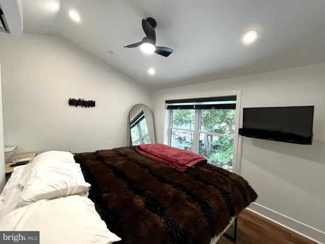 a bedroom with a bed a flat screen tv and a large window