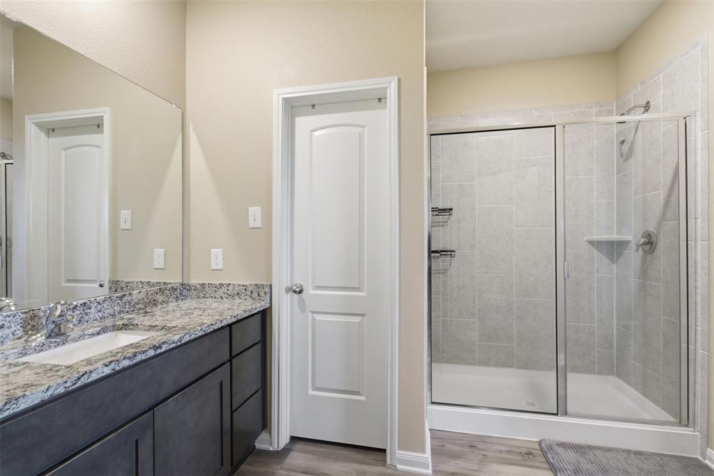292 Wandering Stream Way Princeton, TX 75407 - Photo 28 of 40 Bathroom featuring a shower stall, vanity, and dark wood-style floors