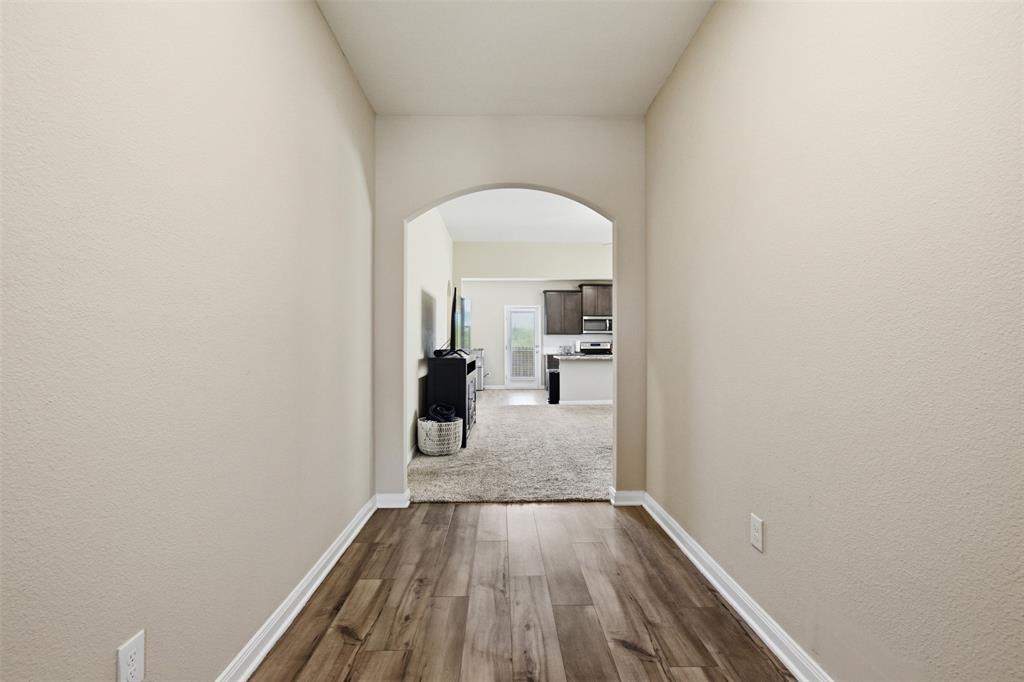 292 Wandering Stream Way Princeton, TX 75407 - Photo 30 of 40 Corridor with arched walkways, dark wood-style flooring, and a textured wall
