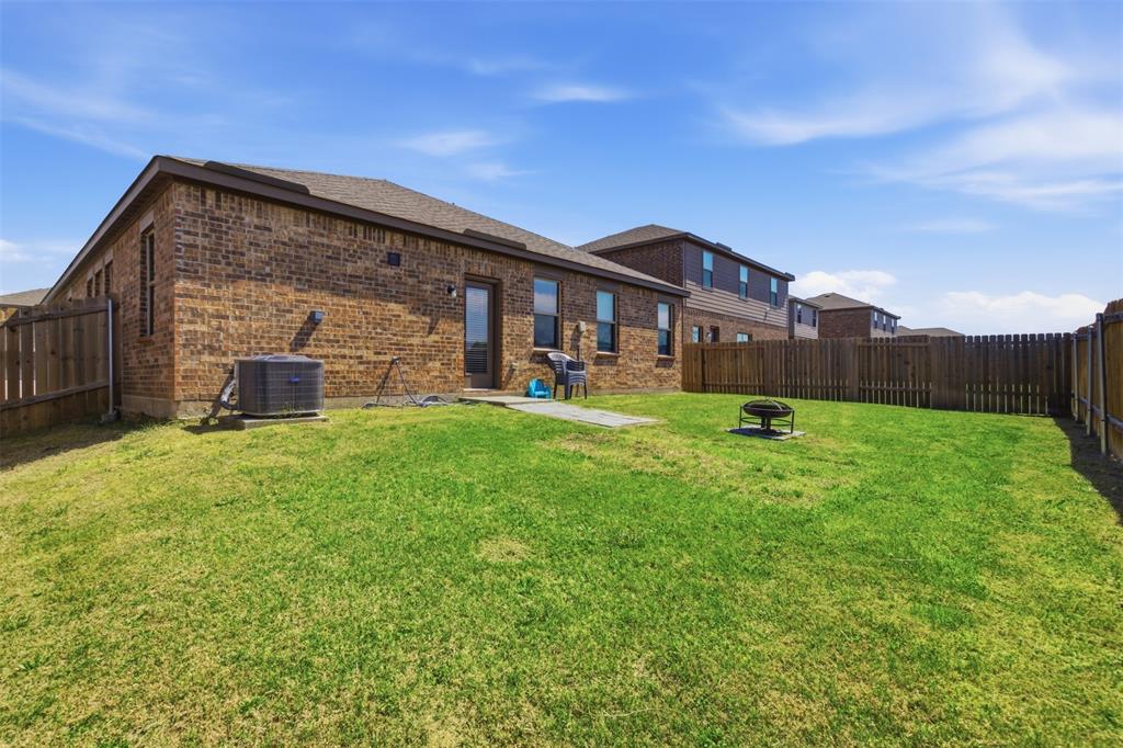 292 Wandering Stream Way Princeton, TX 75407 - Photo 33 of 40 Back of property featuring a fenced backyard, brick siding, and a fire pit