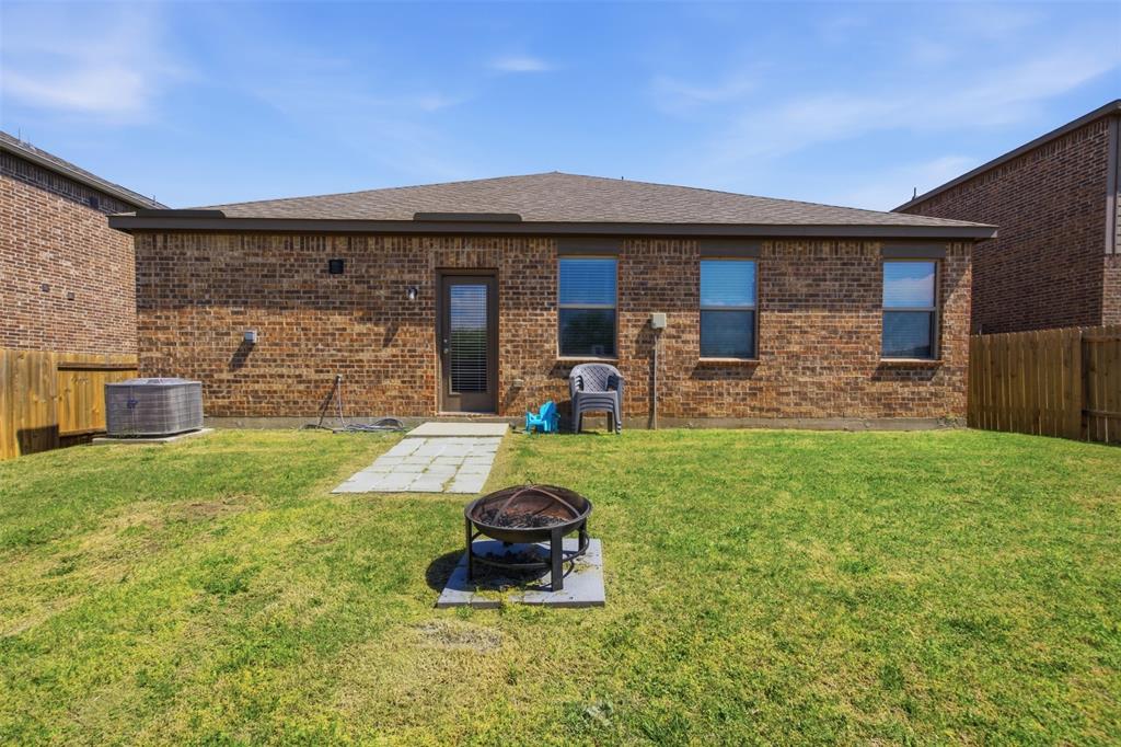 292 Wandering Stream Way Princeton, TX 75407 - Photo 37 of 40 Back of house featuring a fenced backyard, brick siding, a patio, roof with shingles, and an outdoor fire pit