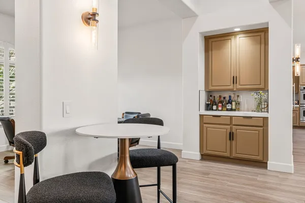 a kitchen with stainless steel appliances kitchen island granite countertop a refrigerator a stove a sink a dining table and chairs with wooden floor