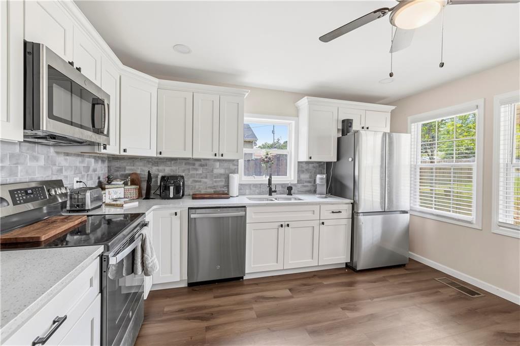 156 Pine Avenue Commerce, GA 30529 - Photo 16 of 35 a kitchen with stainless steel appliances granite countertop a stove a sink dishwasher a refrigerator and white cabinets with wooden floor