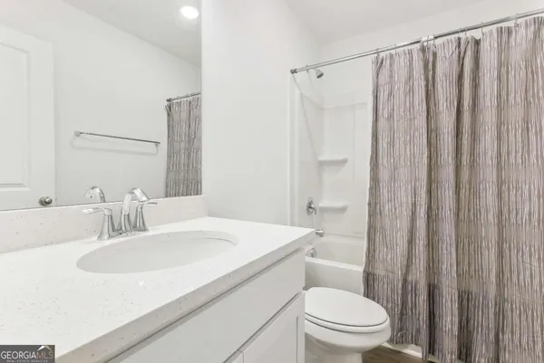 a bathroom with a sink a toilet a mirror and shower curtain