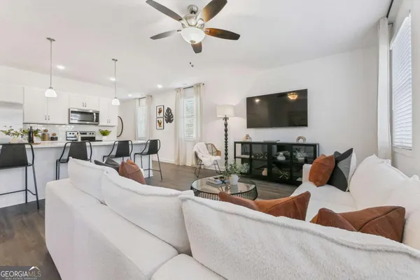 a living room with furniture a flat screen tv and kitchen view