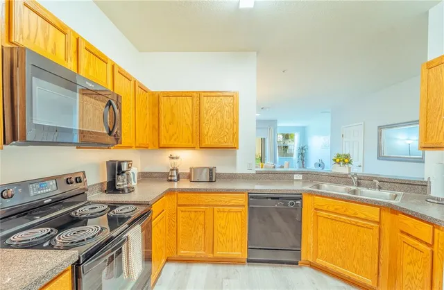 a kitchen with stainless steel appliances granite countertop a sink a stove cabinets counter space and a window