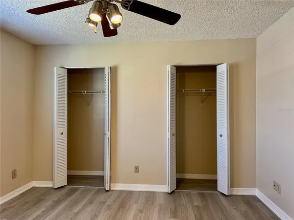 an empty room with wooden floor closet and windows