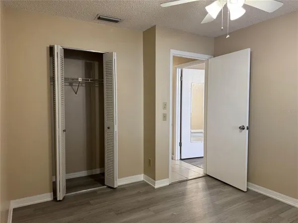 an empty room with wooden floor chandelier and closet area