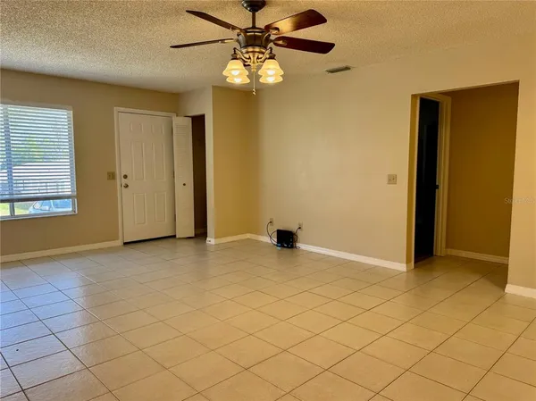 an empty room with windows and fan