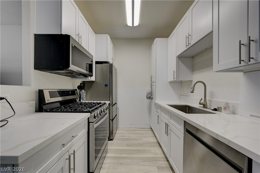 4730 East Craig Road, Unit 1155 Las Vegas, NV 89115 - Photo 11 of 41 A streamlined kitchen showcasing bright white cabinetry and stainless steel appliances.