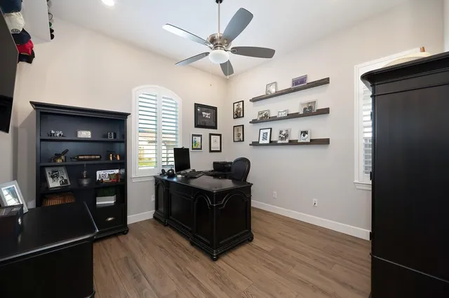 a view of a workspace with furniture and a ceiling fan
