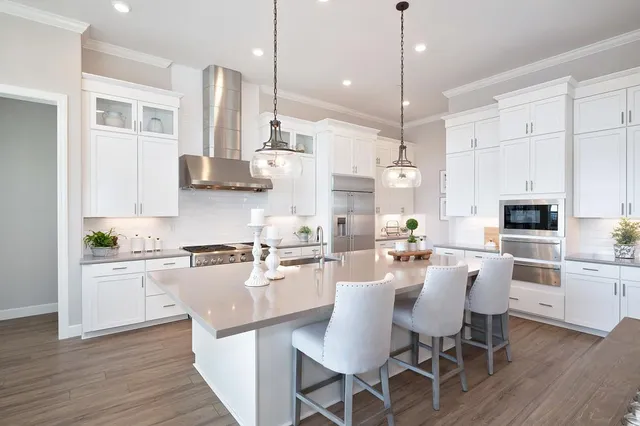 a large kitchen with white cabinets stainless steel appliances a dining table and chairs