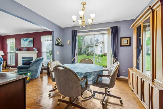 a dining room with wooden floor a chandelier a wooden table and chairs
