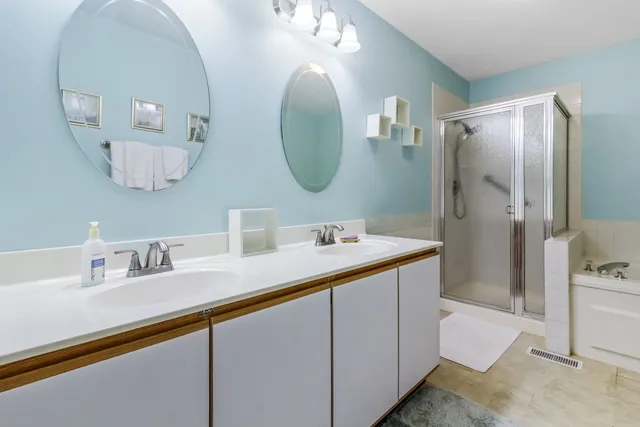 a bathroom with a double vanity sink mirror and shower