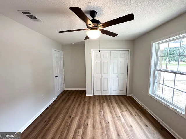 an empty room with wooden floor cabinet and windows