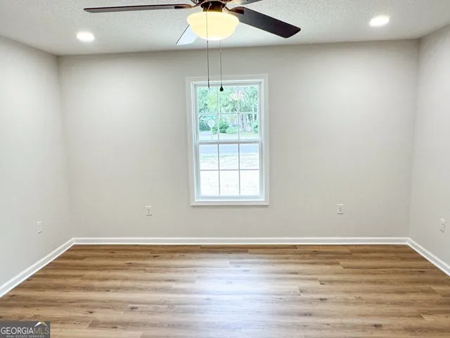 a view of an empty room with window and wooden floor