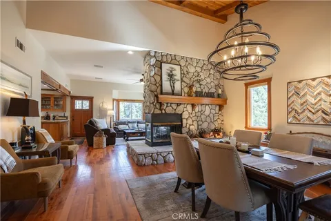 a living room with furniture a fireplace and a dining table with wooden floor