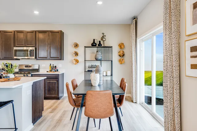 a kitchen with stainless steel appliances granite countertop a stove a refrigerator a microwave and a dining table with wooden floor