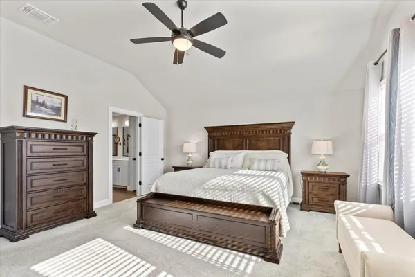 a bedroom with a bed a dresser and a chandelier