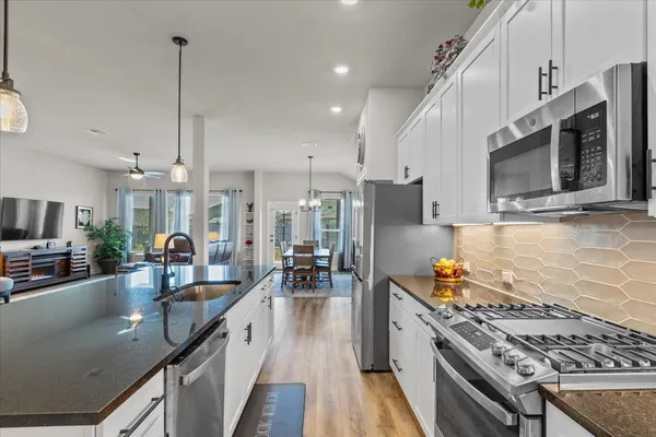 a kitchen with stainless steel appliances granite countertop a sink a stove top oven a counter space and cabinets