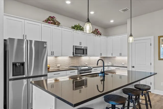 a kitchen with kitchen island granite countertop a sink a center island stainless steel appliances and cabinets