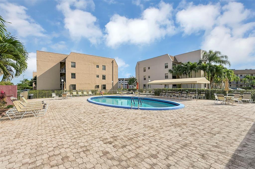 2720 North Pine Island Road, Unit 212 Sunrise, FL 33322 - Photo 42 of 49 a view of a swimming pool with a lawn chairs and potted plants