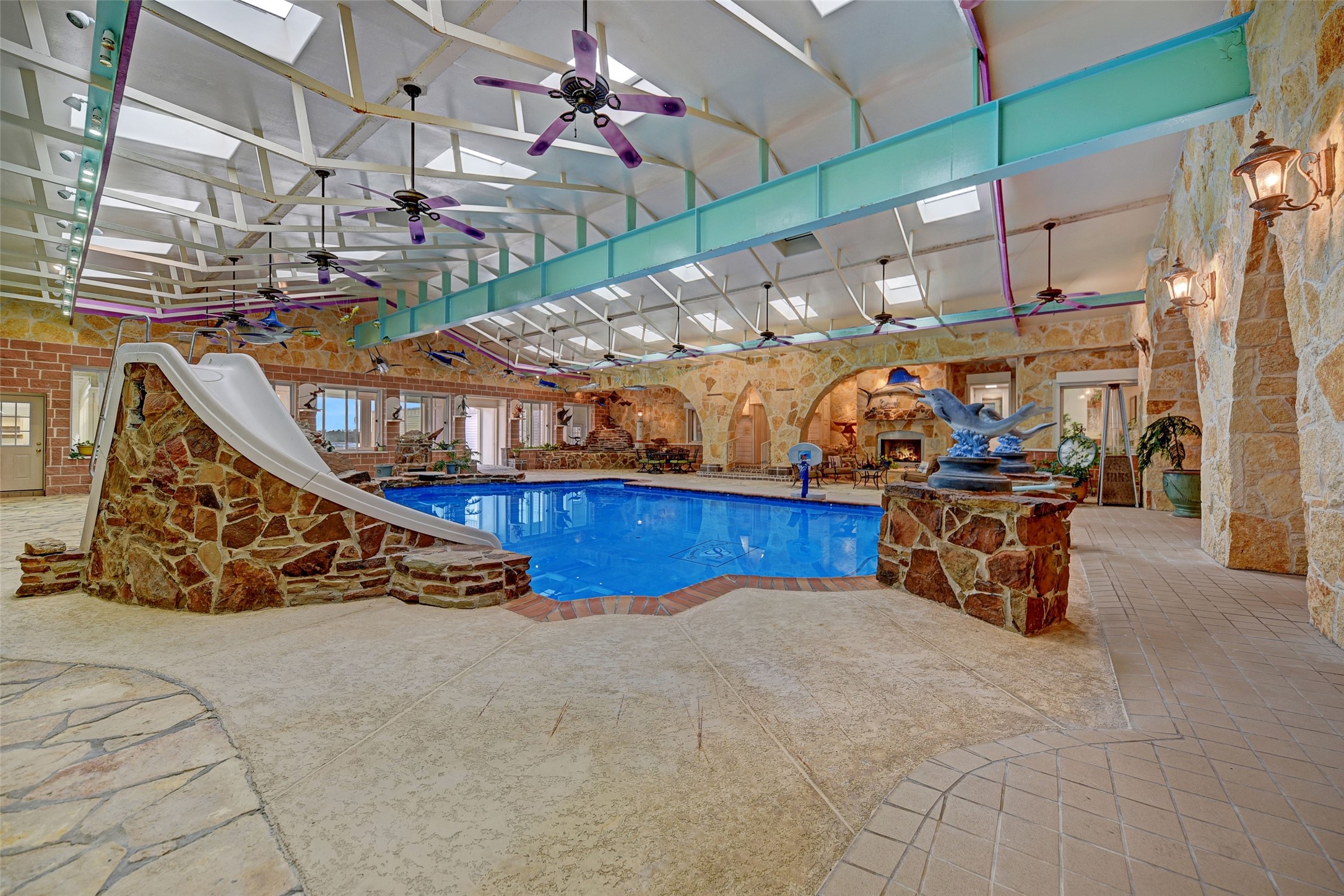 9950 Palestine Road Brenham, TX 77833 - Photo 21 of 49 The home was designed to provide direct access to 4,500 SF recreational pool area from the game room, saloon and commercial dining room areas, front great room, primary suite, or the massive back patio overlooking the land. This area is complete with 16 skylights, pool slide, and a separate pool bath and changing area.