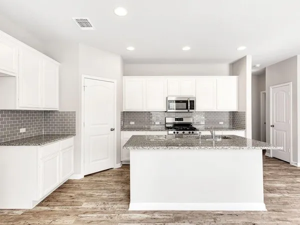 a view of a kitchen with kitchen island a sink a counter top and stainless steel appliances