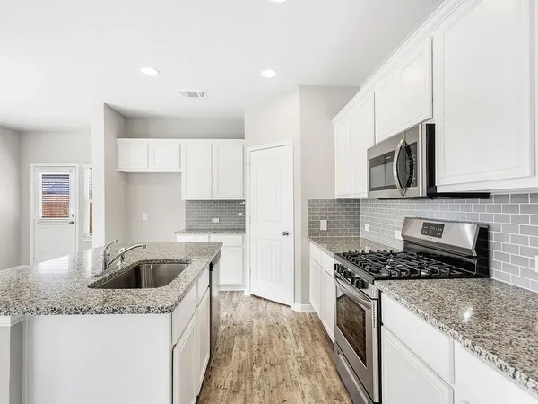 a kitchen with granite countertop stainless steel appliances a stove sink and microwave