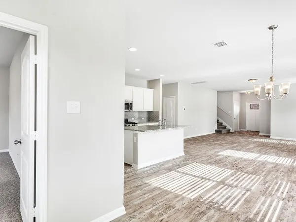 a large white kitchen with kitchen island a sink stainless steel appliances and cabinets