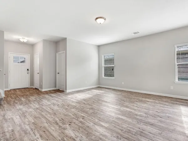 a view of an empty room with wooden floor and window