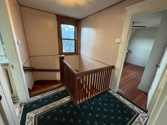 a view of a hallway with wooden floor and staircase